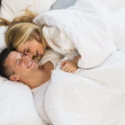 smiling-couple-lying-blanket-bed